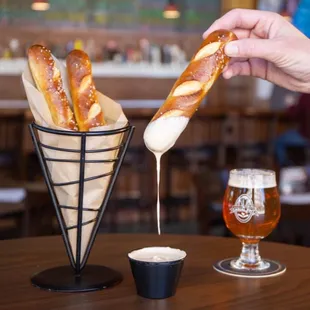 a person dipping a pretzel into a cone
