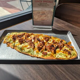 Fig &amp; Bacon Flatbread.  Naan flatbread topped with pesto, mozza, dried figs, bacon, drizzled with spicy Thai chili sauce.