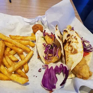 Partially eaten white fish tacos with fries