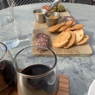 a glass of wine and a plate of meats
