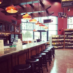 a bar with stools and bottles of wine
