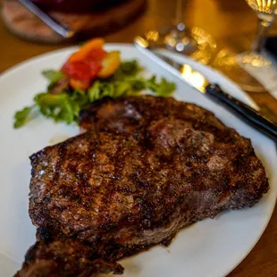 a steak on a plate with a side salad
