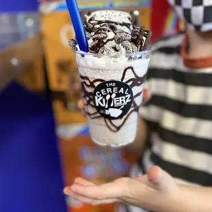 a person wearing a mask and holding a cup of milkshake