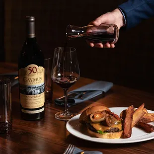 A true classic reimagined! The Grind n&apos; Vine pairs our signature burger with a glass of Caymus wine for an unforgettable dining experience.