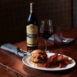 A true classic reimagined! The Grind n&apos; Vine pairs our signature burger with a glass of Caymus wine for an unforgettable dining experience.