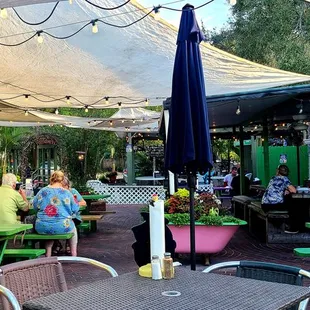 a group of people sitting at tables under umbrellas