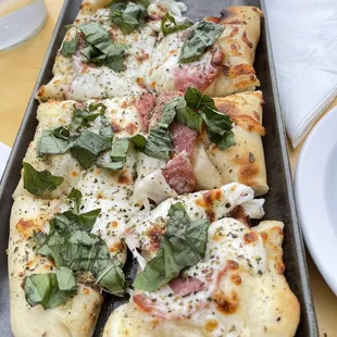 a pizza with ham, cheese, and spinach