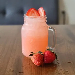 a jar of strawberryade and two strawberries