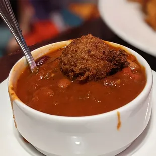 Cup of quinoa chili with corn fritters, complete with spills on the side