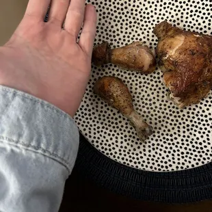a person holding a piece of chicken