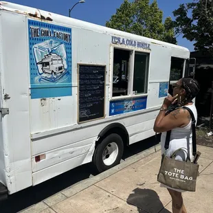 a woman taking a picture of a food truck