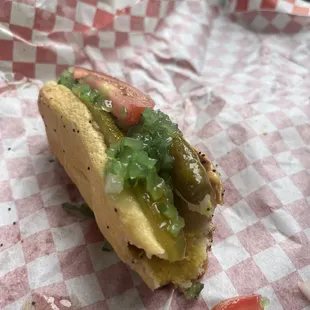 a photo of a partially bitten vegan Chicago hot dog to relish the moment for longer. Check out that sport pepper.