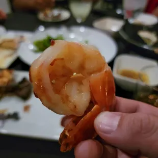 a hand holding a piece of shrimp