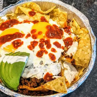 Chorizo Chilaquiles - Sunnyside eggs, chorizo, tortilla chips, chihuahua cheese, sour cream, avocado, salsa rojo