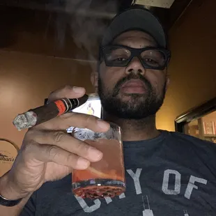 a man holding a cigar and a glass
