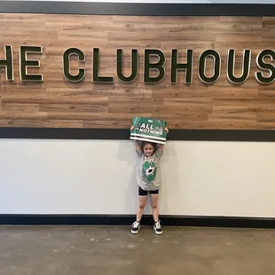 a young boy holding a box of pizza