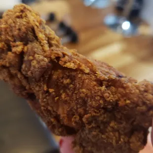 a hand holding a piece of fried chicken