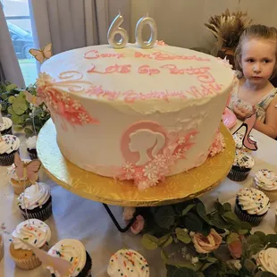 a young girl standing in front of a cake