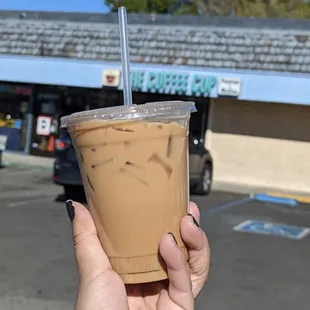 a hand holding a cup of iced coffee