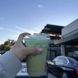 a hand holding a cup of green tea