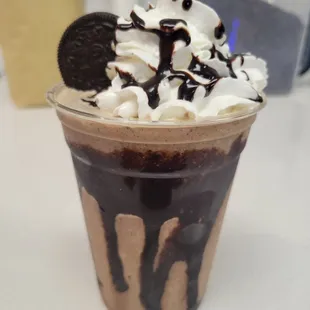 a chocolate milkshake with whipped cream and oreo cookies