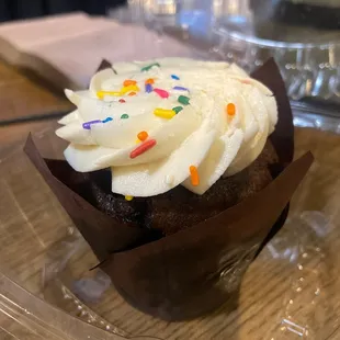 a cupcake with white frosting and sprinkles