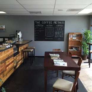 Inside view of front counter, bar seating, table and coffee flow chart .