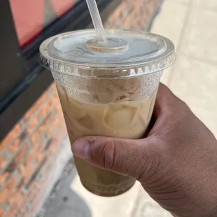a hand holding a cup of iced coffee