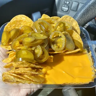 a person holding a tray of nachos