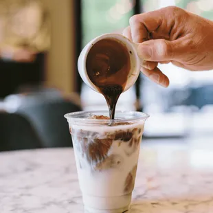 a person pouring chocolate into a cup