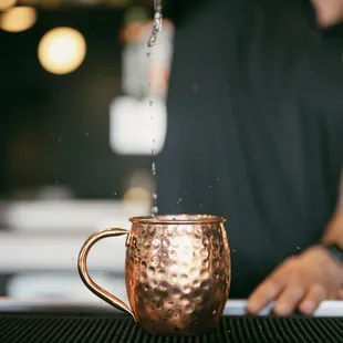  man pouring water into a copper mug