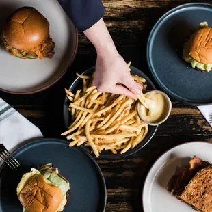 a person grabbing a plate with a burger and french fries