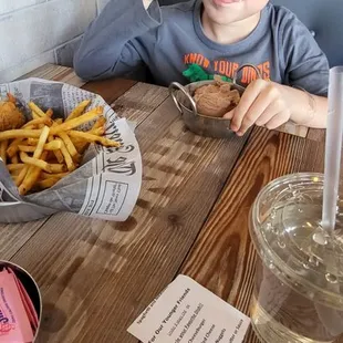 Brat with chocolate ice cream and bowl of chicken nuggets and fries.