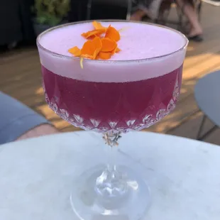 a purple cocktail with orange garnish