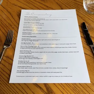 a menu on a table with a fork and knife