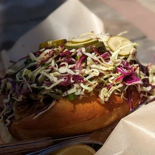 a hot dog with coleslaw and pickles