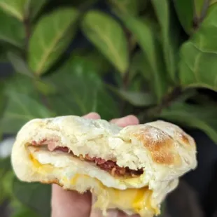 a hand holding a breakfast sandwich