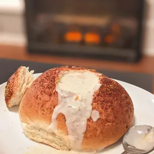 a white plate with a hot dog bun and a spoon