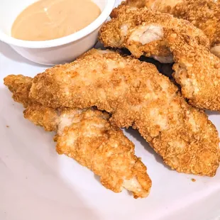 a plate of fried chicken strips with dipping sauce