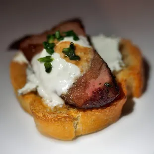 Filet mignon crostini. Herbed Chevre cheese with filet mignon, horseradish sour cream and balsamic glaze.