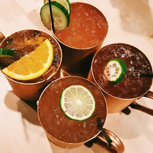 (Starting clockwise from the orange slice) The Garden, Cucumber Lime, Pomegranate, and Spiced Pear Moscow Mules.
