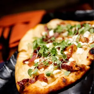 a flatbread pizza on a black plate