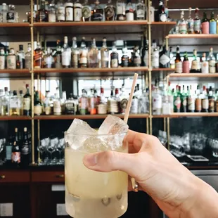 a person holding a drink in front of a bar