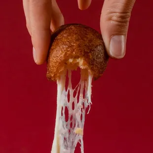 a hand holding a piece of cheese