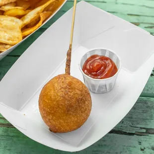 a corndog with ketchup and chips