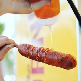 a hot dog being drizzled with mustard