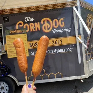 a person holding two corndogs