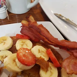Pancakes with strawberries, bananas and a side of bacon.