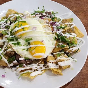Chilaquiles with Verde (green) sauce, asada, and sunny side up eggs.