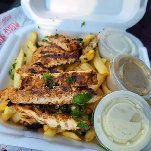 Chicken over fries with garlic sauce, hummus and ranch